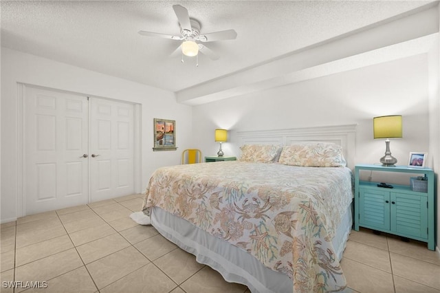 bedroom with light tile patterned floors, a textured ceiling, a ceiling fan, and a closet