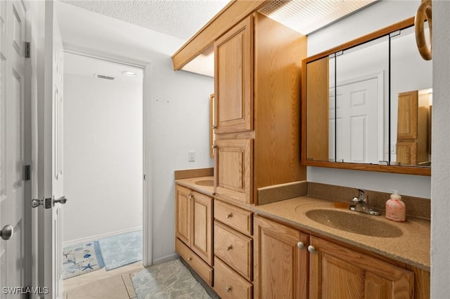 bathroom featuring a textured ceiling, double vanity, tile patterned flooring, and a sink