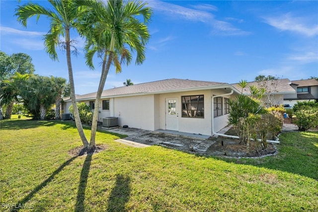 rear view of house with a yard, central AC unit, and stucco siding