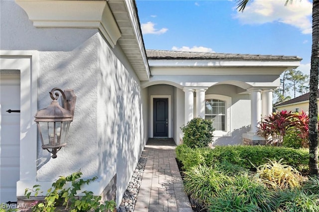 doorway to property featuring an attached garage and stucco siding