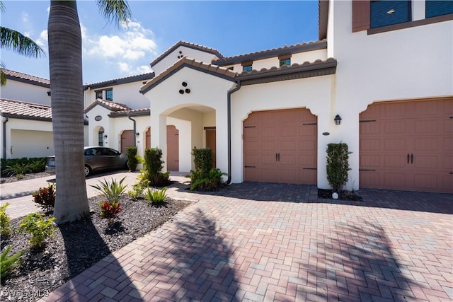 mediterranean / spanish home with a tile roof, decorative driveway, and stucco siding