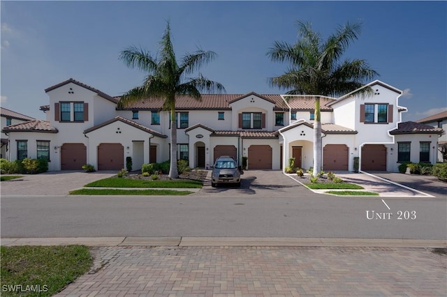 mediterranean / spanish home featuring a garage, decorative driveway, and a tile roof