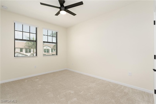 spare room featuring ceiling fan, baseboards, and light colored carpet