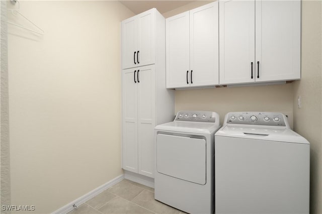 laundry room with baseboards, light tile patterned flooring, cabinet space, and washer and dryer