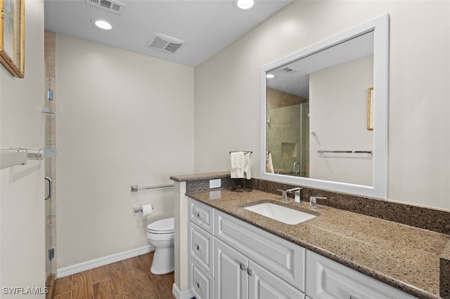 full bath with toilet, a stall shower, wood finished floors, and visible vents