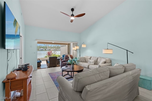 living area with vaulted ceiling, light tile patterned floors, a water view, and a ceiling fan