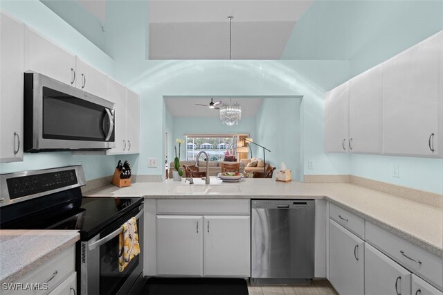 kitchen with white cabinets, a sink, stainless steel appliances, light countertops, and a notable chandelier