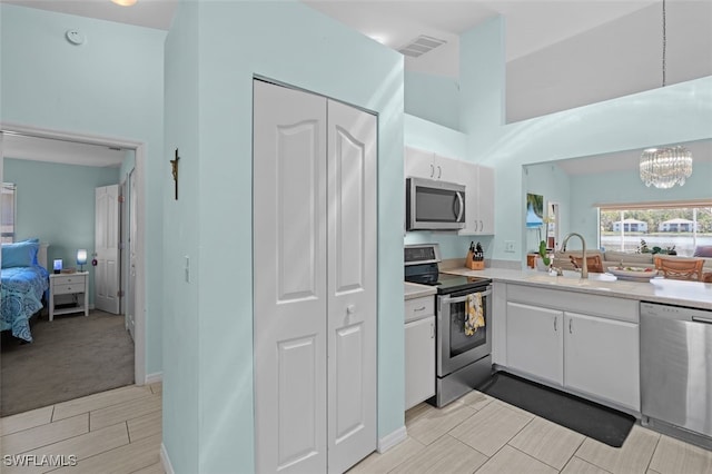 kitchen with stainless steel appliances, a sink, visible vents, white cabinetry, and light countertops