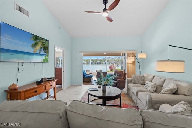 living area featuring visible vents, a water view, a ceiling fan, high vaulted ceiling, and baseboards