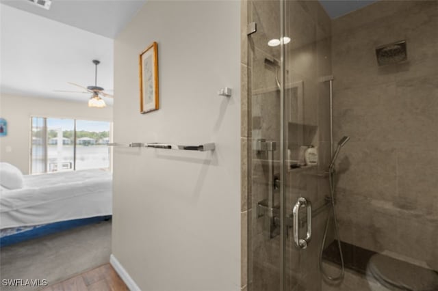 ensuite bathroom with a ceiling fan, a stall shower, ensuite bath, wood finished floors, and baseboards