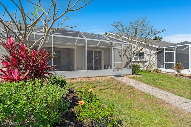 back of property featuring a yard, glass enclosure, and stucco siding