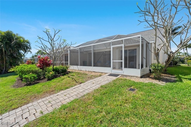 back of property featuring a yard and glass enclosure