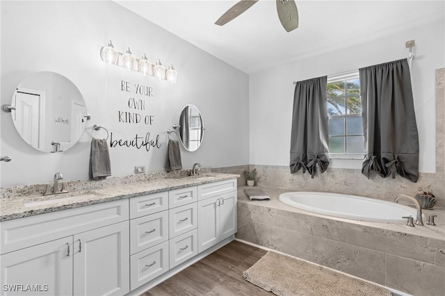 bathroom with double vanity, wood finished floors, a sink, and a bath