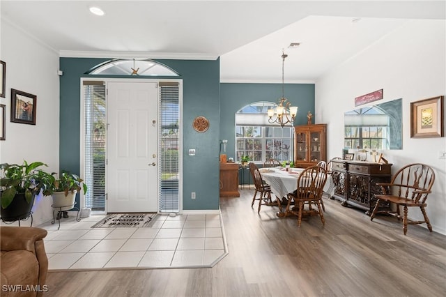 foyer with wood finished floors, a healthy amount of sunlight, crown molding, and an inviting chandelier