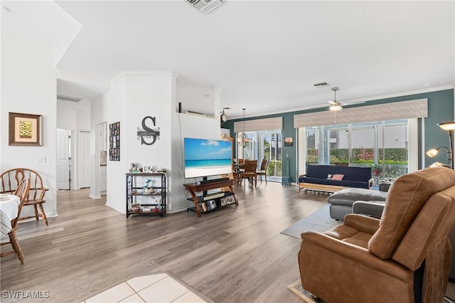 living room with ornamental molding, wood finished floors, and visible vents