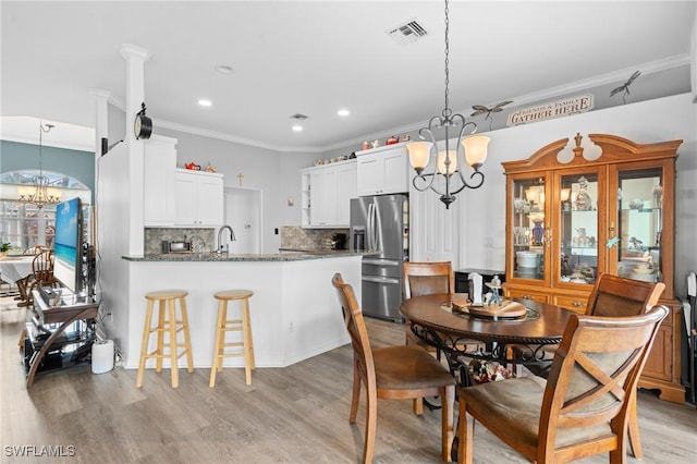 dining space featuring crown molding, a notable chandelier, recessed lighting, visible vents, and light wood-style flooring