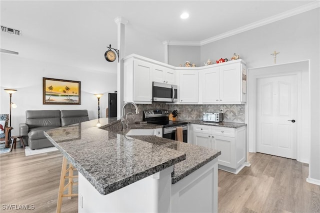 kitchen featuring stainless steel appliances, white cabinets, visible vents, and a peninsula