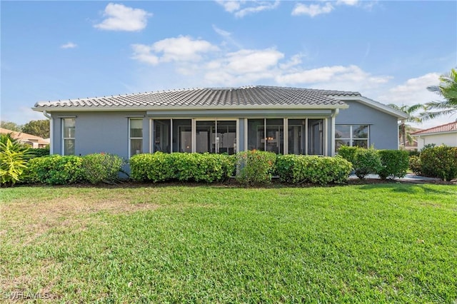 view of front of home featuring a front yard, a tile roof, a sunroom, and stucco siding