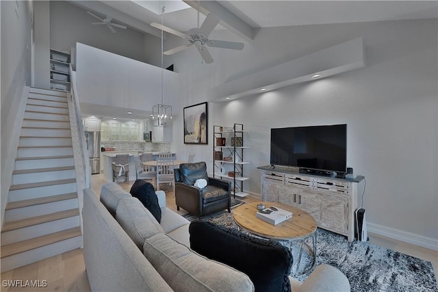 living room featuring ceiling fan, light wood finished floors, stairs, and baseboards