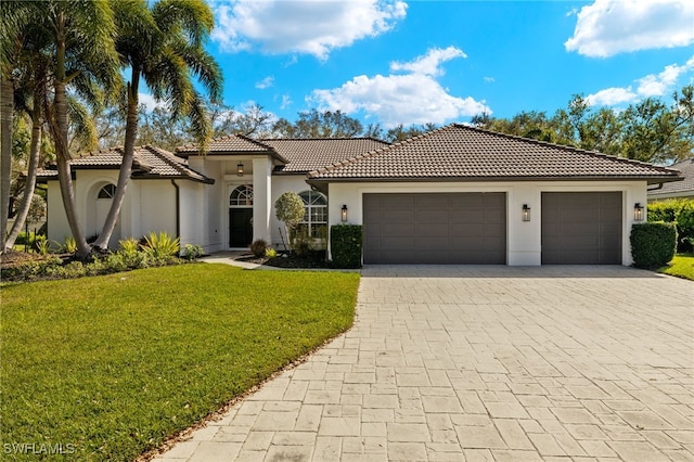 11211 Mahogany Run, Fort Myers, FL 33913 - mediterranean / spanish-style home featuring an attached garage, decorative driveway, stucco siding, a front lawn, and a tiled roof