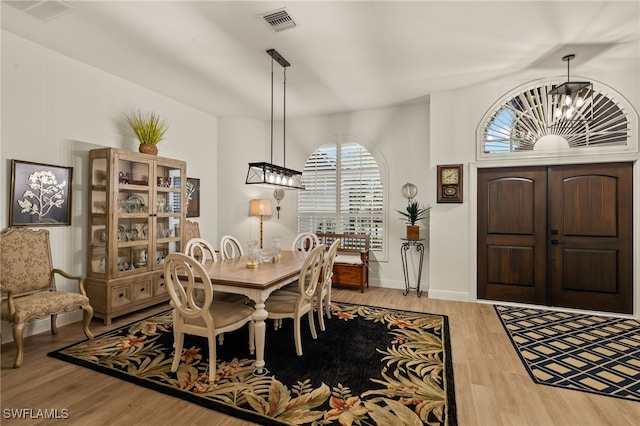 dining space featuring light wood-type flooring, visible vents, baseboards, and an inviting chandelier