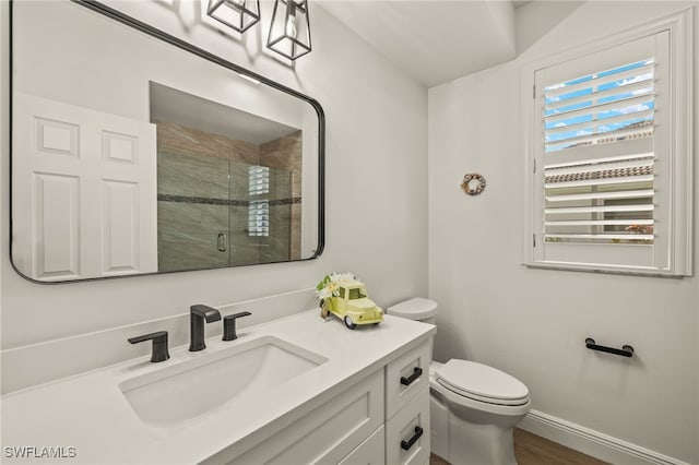 bathroom featuring a stall shower, baseboards, vanity, and toilet