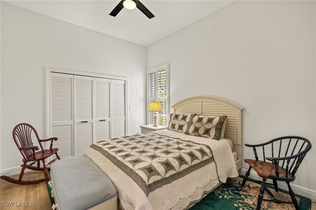 bedroom with a closet, wood finished floors, a ceiling fan, and baseboards