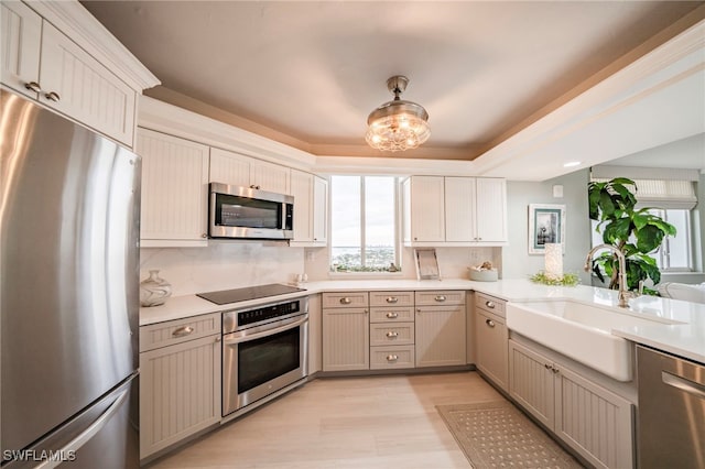 kitchen featuring a sink, light countertops, appliances with stainless steel finishes, light wood-type flooring, and decorative backsplash