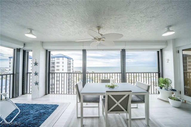 sunroom / solarium featuring a water view and a ceiling fan