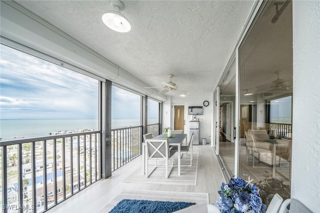 sunroom / solarium featuring a water view and ceiling fan