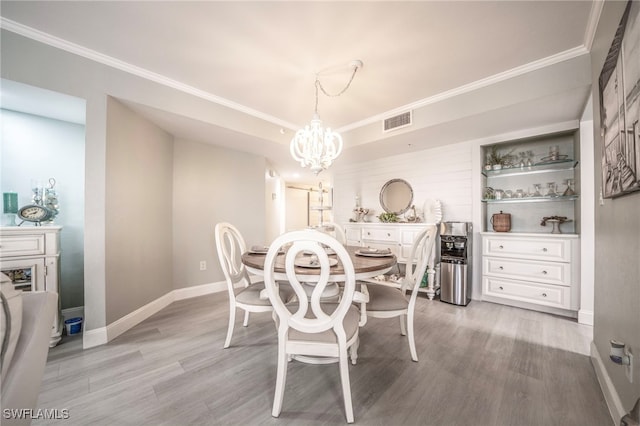 dining room featuring a notable chandelier, visible vents, baseboards, light wood-style floors, and ornamental molding