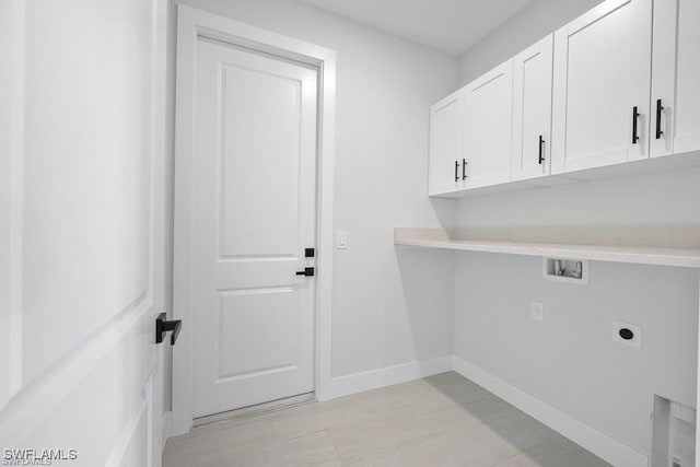 clothes washing area with electric dryer hookup, baseboards, cabinet space, and washer hookup