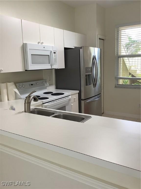 kitchen featuring white appliances, light countertops, and white cabinetry