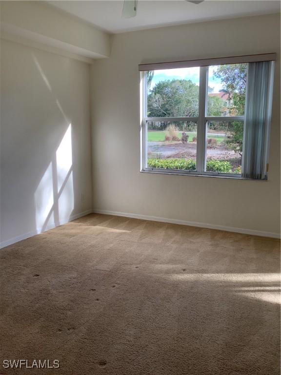 carpeted spare room with ceiling fan and baseboards