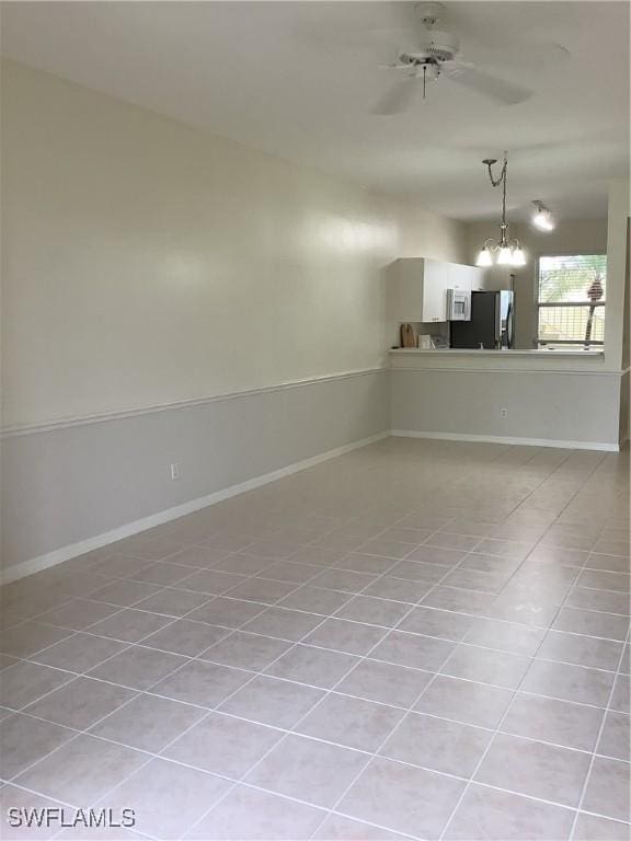 unfurnished room with light tile patterned floors, baseboards, and ceiling fan with notable chandelier