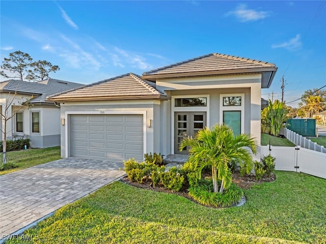 view of front of home with a garage, fence, decorative driveway, a front yard, and stucco siding