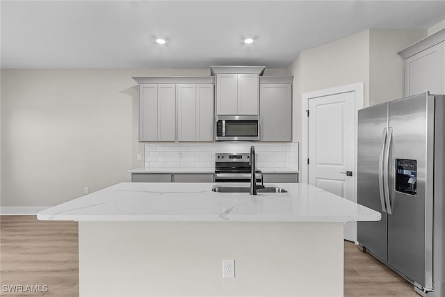 605 SW 21st Ter, Cape Coral, FL 33991 - kitchen featuring stainless steel appliances, a sink, light wood-style flooring, tasteful backsplash, and light stone counters