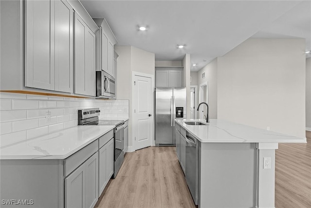 605 SW 21st Ter, Cape Coral, FL 33991 - kitchen featuring appliances with stainless steel finishes, gray cabinets, a sink, light wood finished floors, and a center island with sink