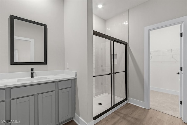 605 SW 21st Ter, Cape Coral, FL 33991 - bathroom with wood finished floors, a stall shower, a spacious closet, vanity, and baseboards