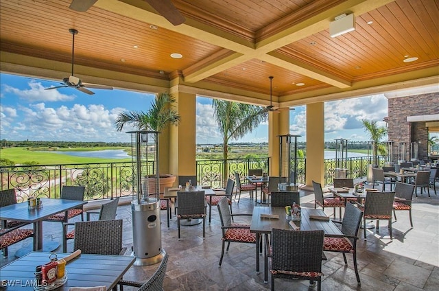 view of patio featuring a ceiling fan, outdoor dining space, and a water view