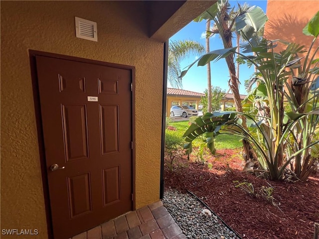 doorway to property with visible vents and stucco siding