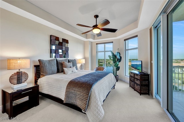 bedroom with carpet flooring, a raised ceiling, a ceiling fan, and access to exterior