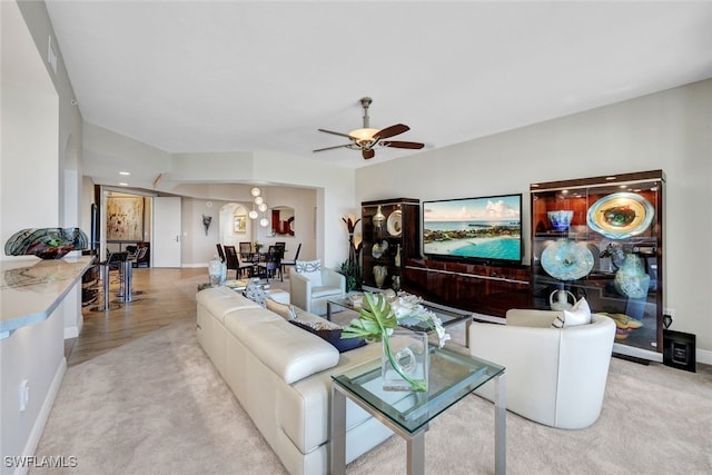 living room featuring carpet floors, baseboards, and a ceiling fan