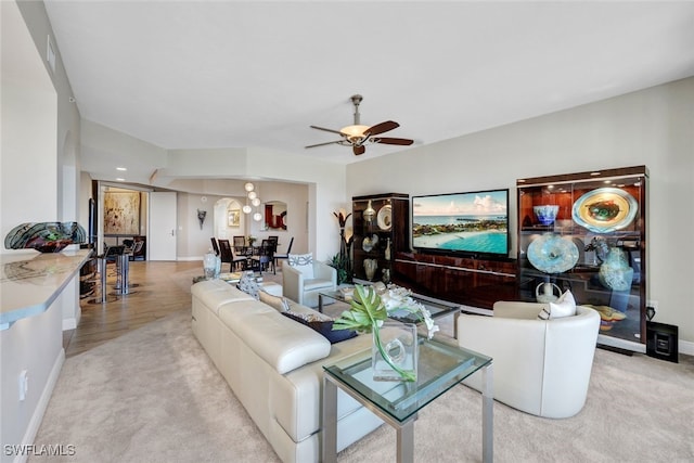 living area featuring a ceiling fan, baseboards, and carpet flooring