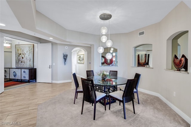 dining room featuring arched walkways, wood finished floors, visible vents, and baseboards