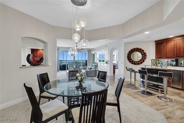 dining area with arched walkways, baseboards, light wood-style flooring, and recessed lighting