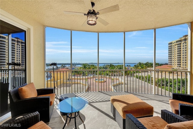 sunroom / solarium featuring ceiling fan, a textured ceiling, a water view, and a wealth of natural light