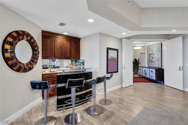 bar featuring light wood-type flooring, visible vents, baseboards, and recessed lighting