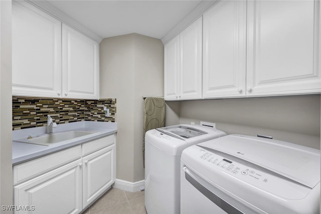 washroom featuring light tile patterned flooring, a sink, baseboards, independent washer and dryer, and cabinet space