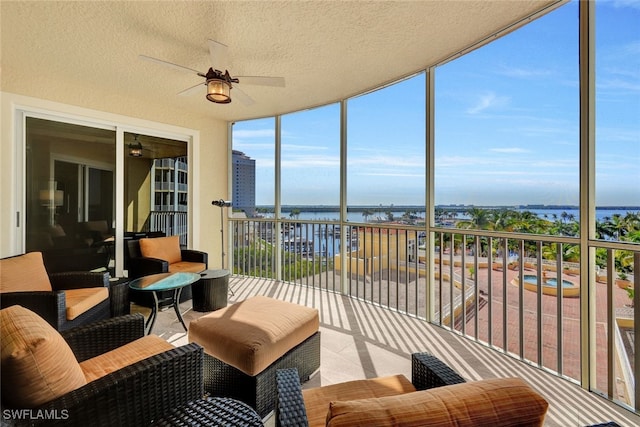 sunroom with a ceiling fan and a water view